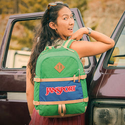 JanSport Retro Seattle Pack in der Farbe Jelly Kelly, getragen von einem lächelnden Mädchen