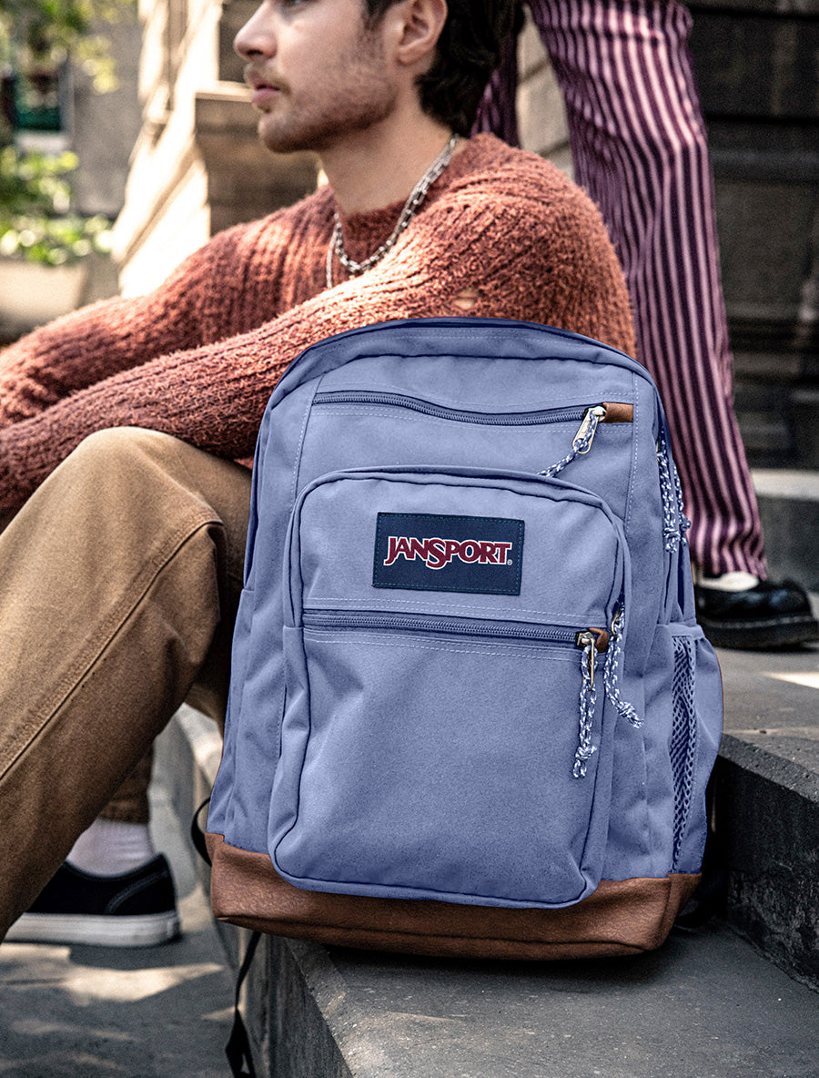 Eine coole JanSport-Schülertasche in Lavendel auf einigen Schultreppen