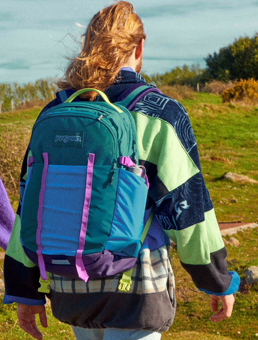 Person mit einem farbenfrohen JanSport All Around Rucksack im Freien
